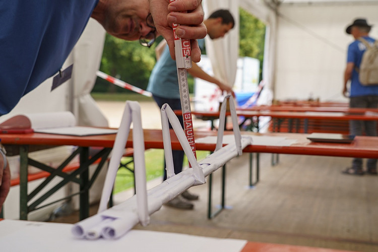 Eine Papierbrücke wird beim Explore Science-Wettbewerb mit einem Zollstock auf ihre Stabilität geprüft.