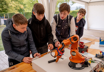 Jugendliche steuern an der Station des Team robOTTO der Otto-von-Guericke-Universität Magdeburg einen Roboterarm.